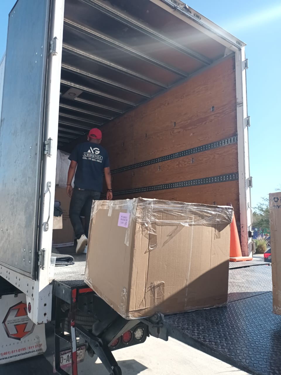 AG Logistics branded truck with crew unloading wrapped freight at destination